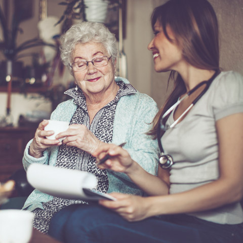 woman holding clipboard while talking with elderly woman