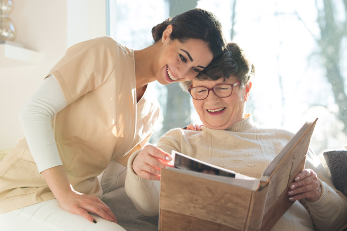 elderly woman shows scrapbook to care giver